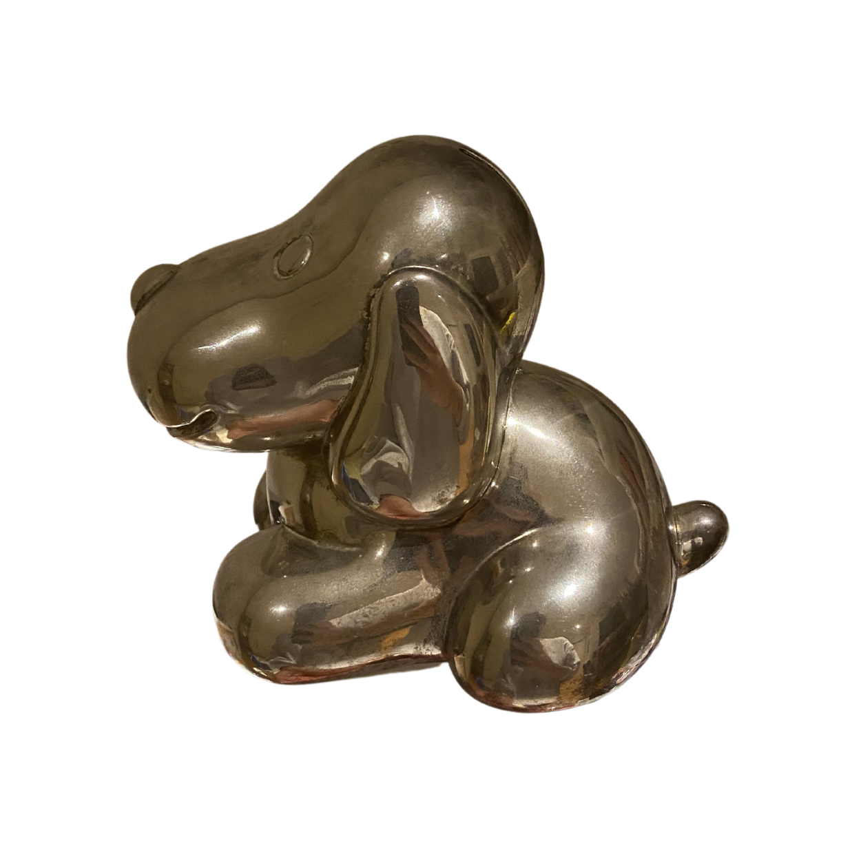 A photo of a small piggy bank in the shape of a hound, made of brass facing left.